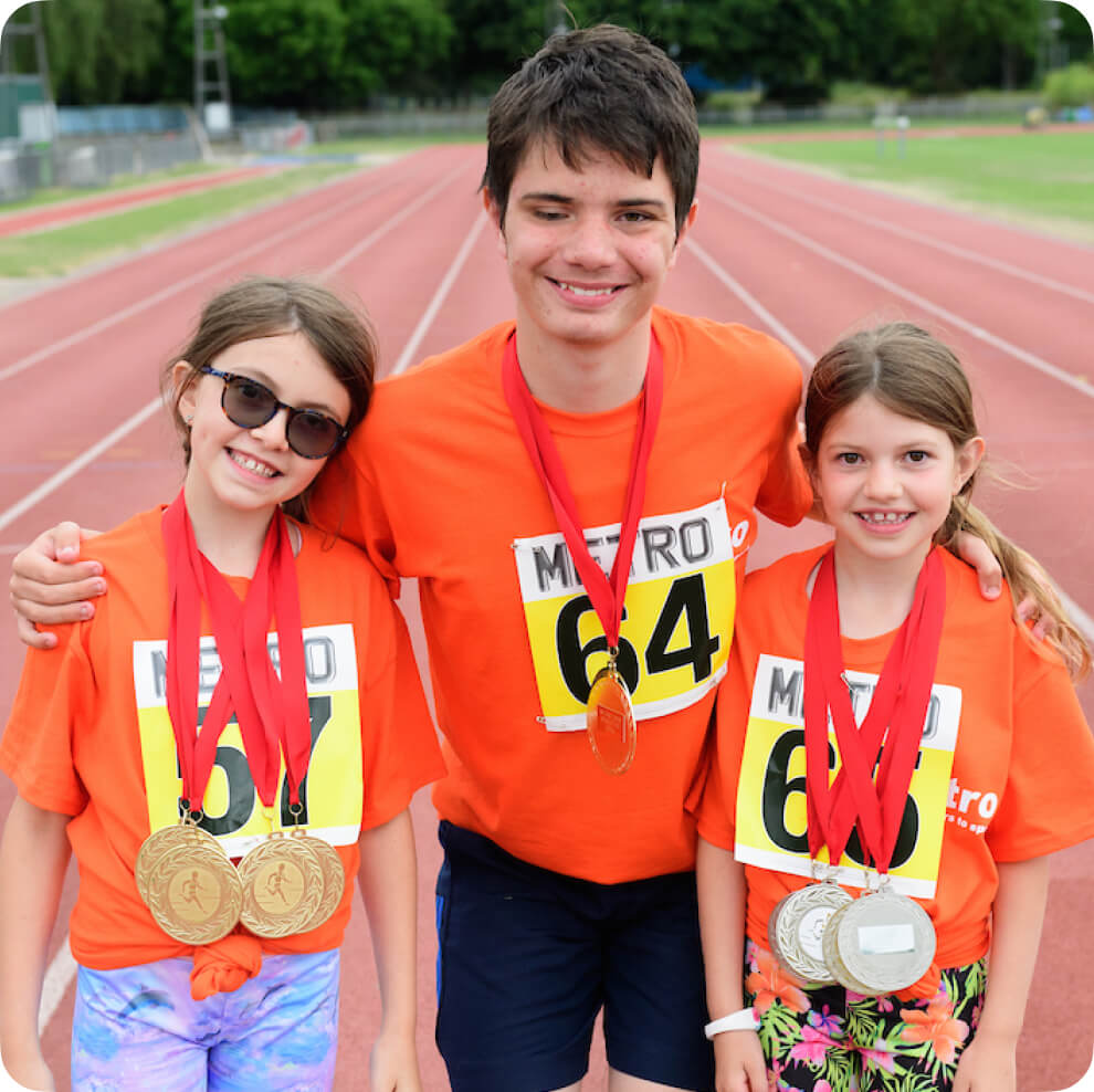 three kids with medals posing for a photo